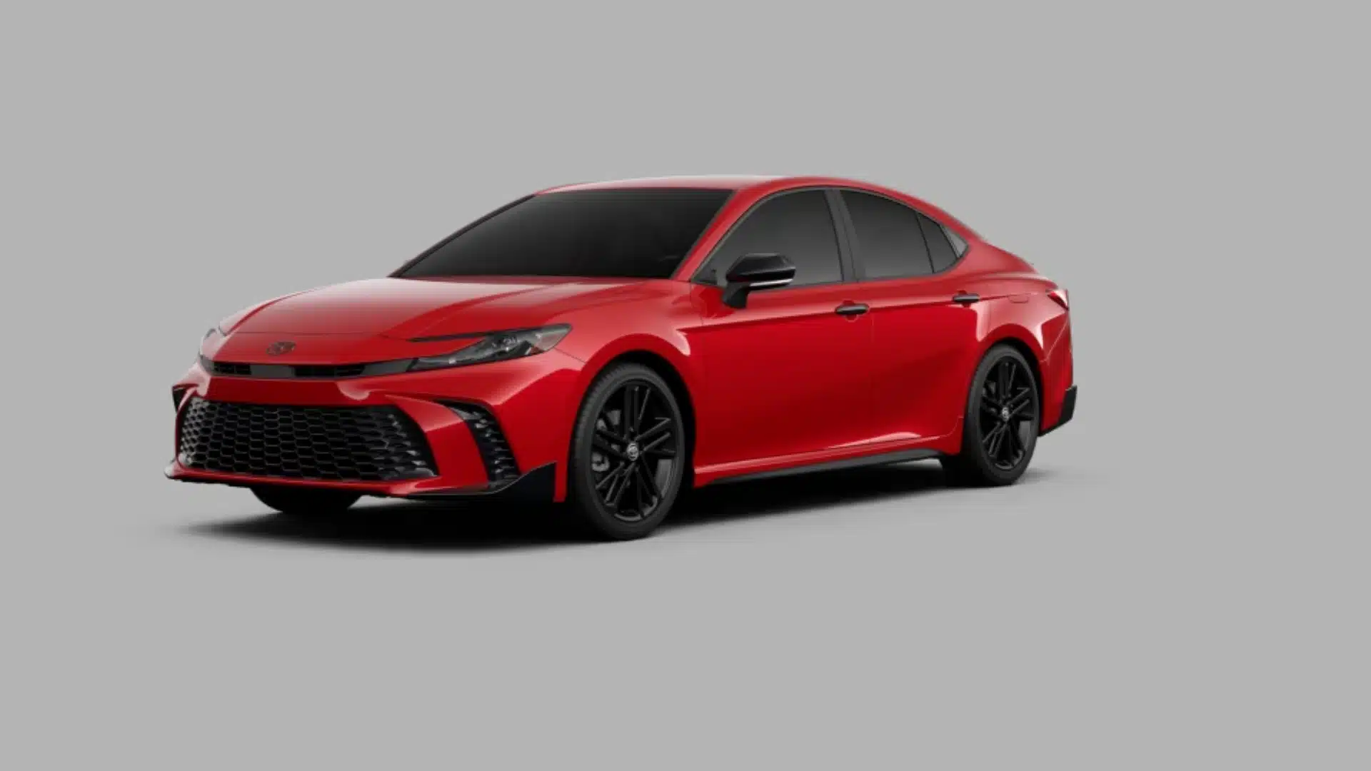 Red Toyota Camry hybrid sedan with black wheels and sporty front styling on a gray background