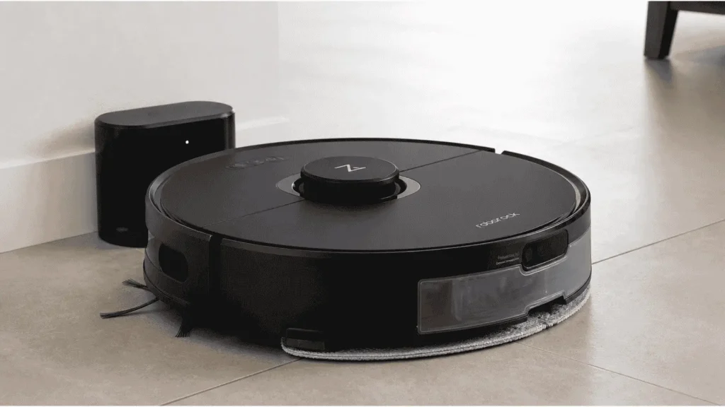 Roborock S6 MaxV with SnapMop water tank attached next to its charging dock on tile floor
