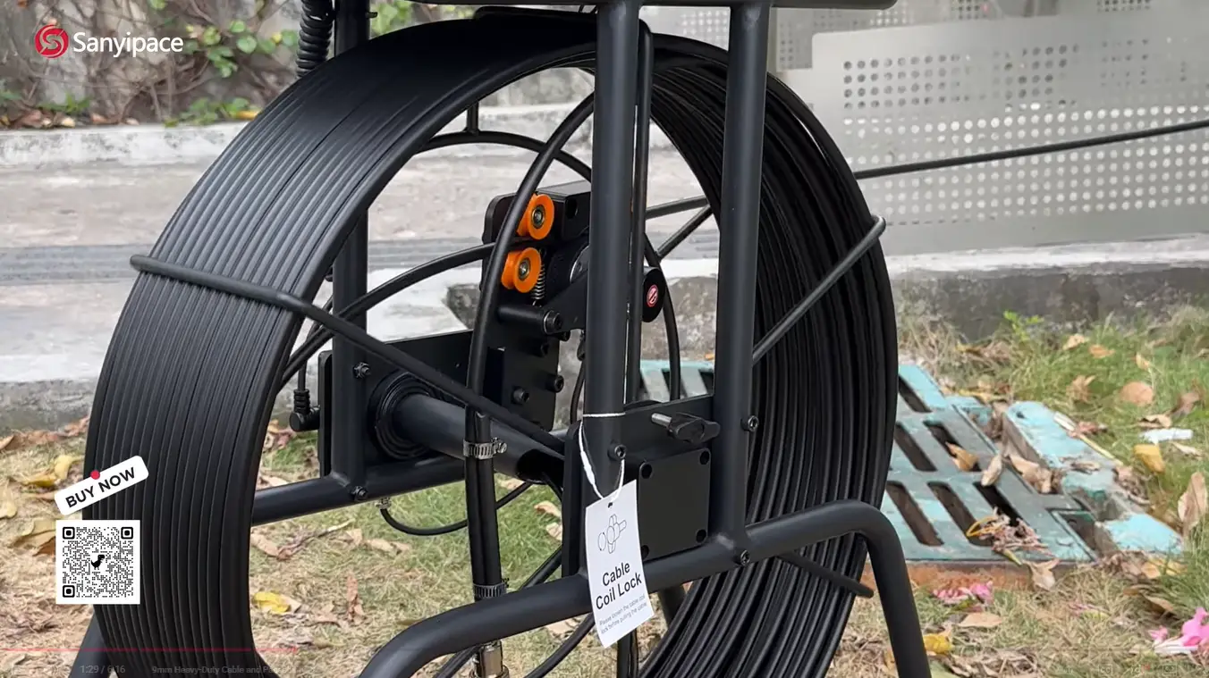 Heavy-duty black cable coil on metal reel stand outdoors on grass