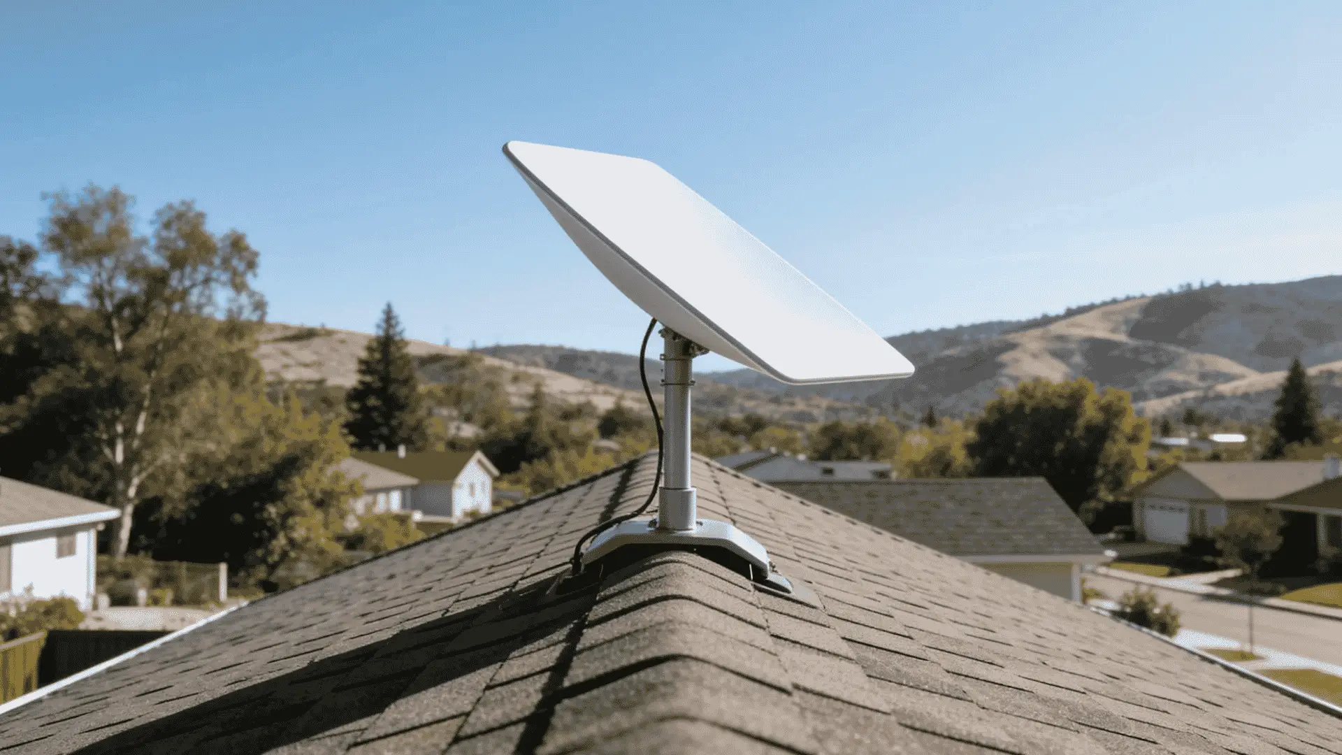 Starlink satellite dish installed on a residential roof with hills and neighborhood homes in the background