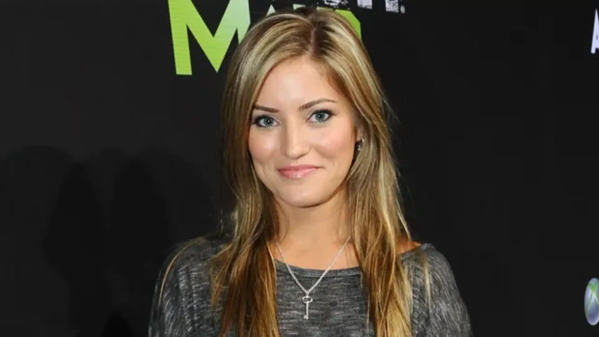 Tech creator Justine Ezarik posing in front of a dark event backdrop with gaming and tech logos