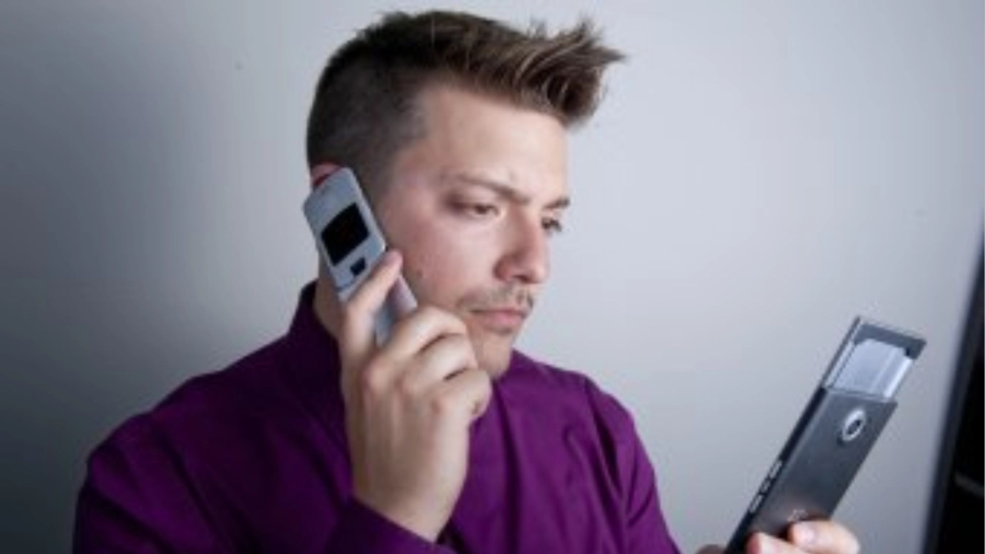 Tech reviewer comparing two smartphones while holding one to his ear