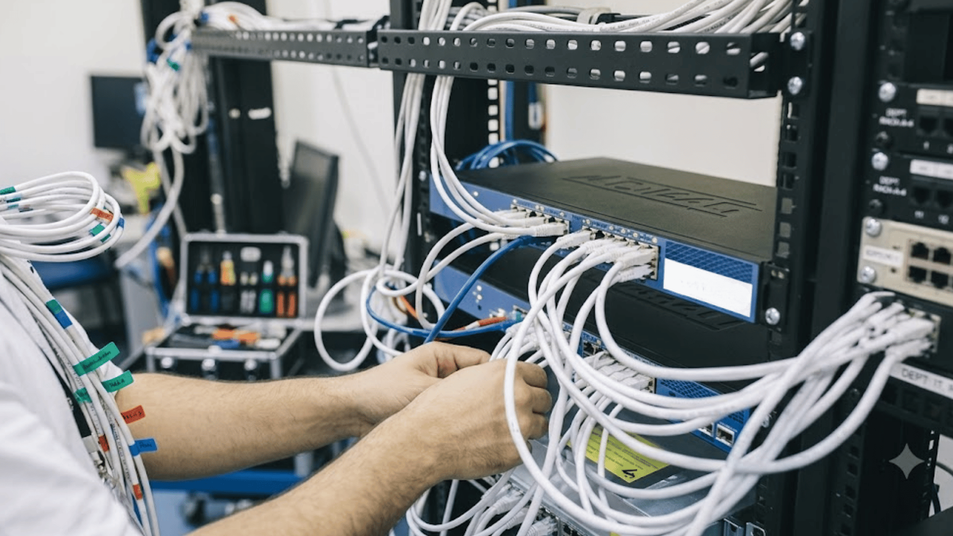 technician connecting network cables in a server rack while organizing wired connections in a data center setup