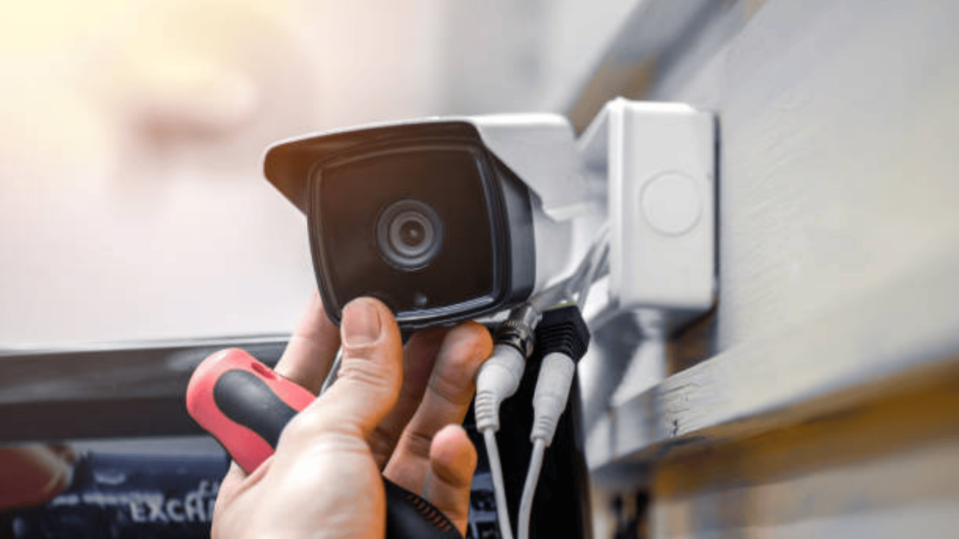 technician installing an outdoor security camera with cables connected to the wall mount