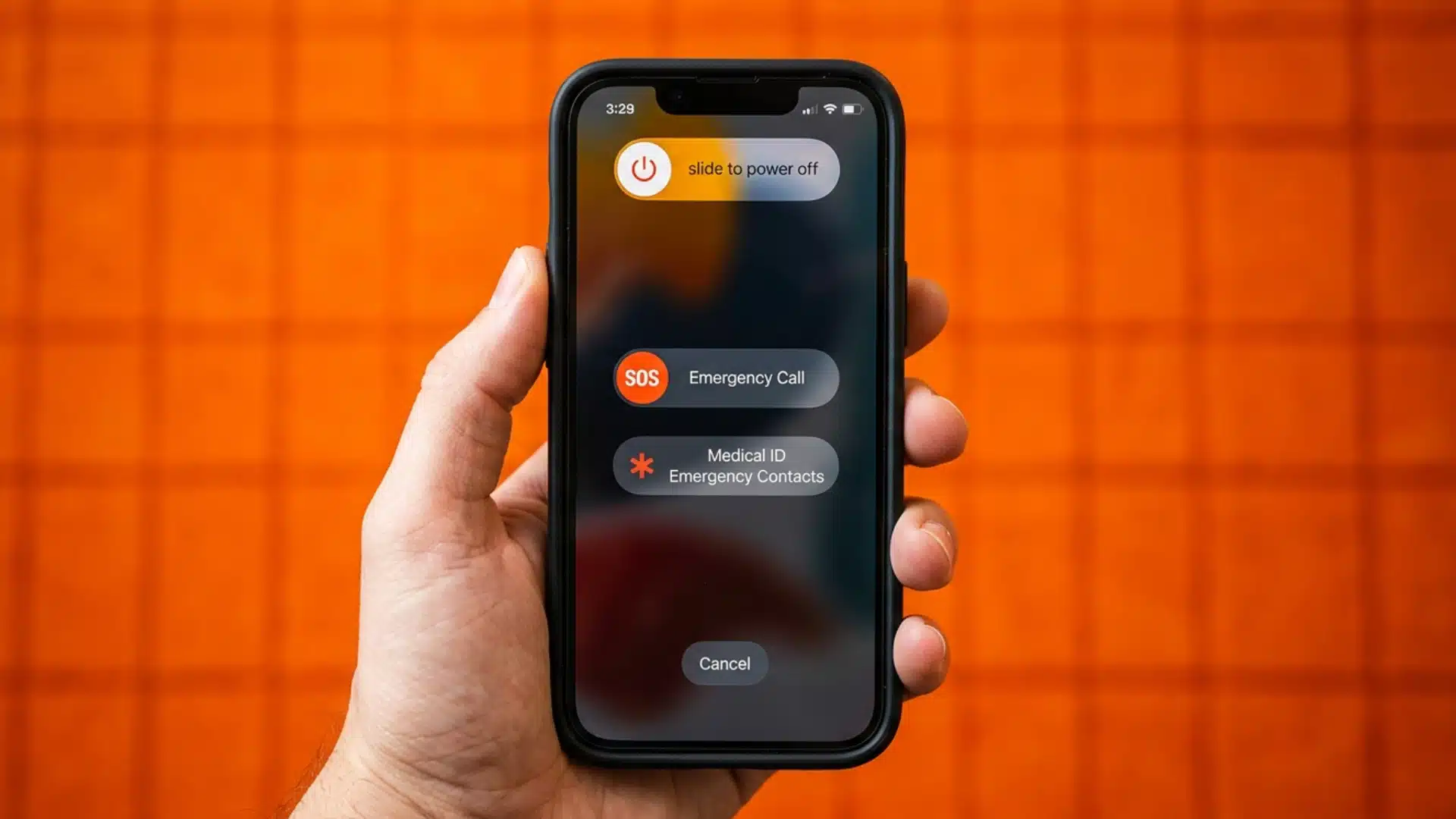 A hand holding an iPhone showing the power off and emergency sliders against a bright orange grid background
