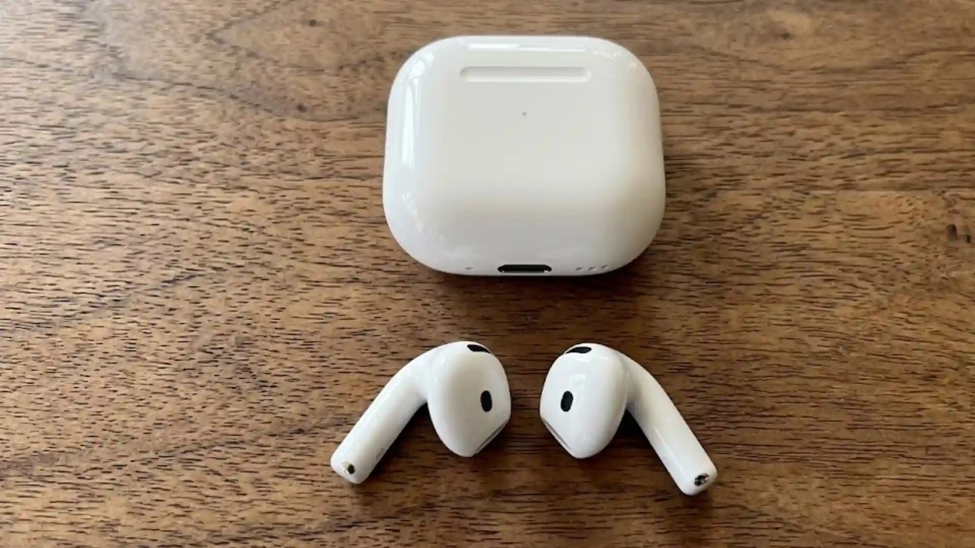 AirPods 4 earbuds and charging case placed on a wooden table
