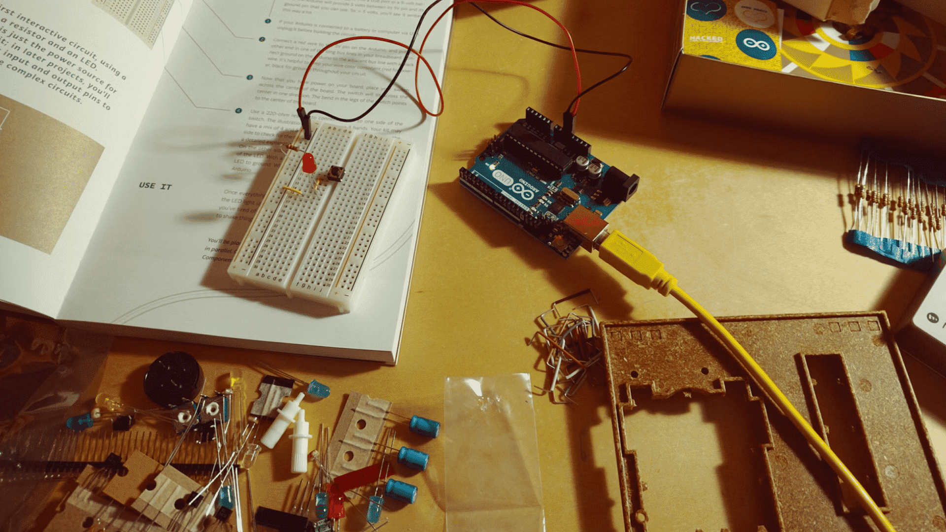 arduino starter kit with breadboard components instruction book and connected microcontroller on a workbench