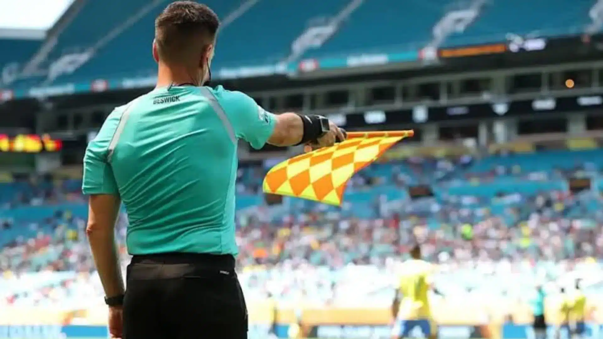 Assistant referee raising flag during a football match in a stadium