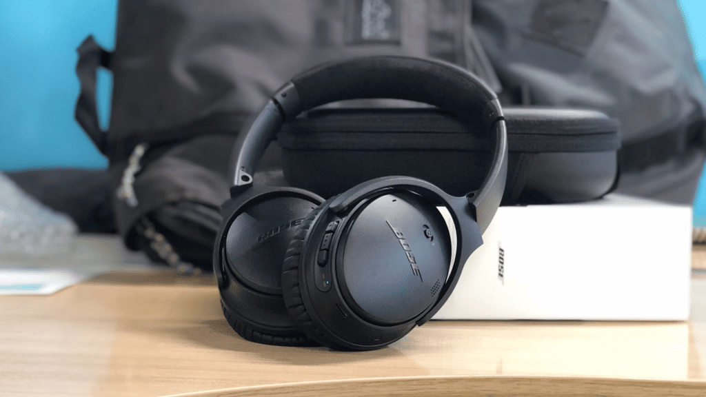 black bose over ear headphones displayed on a desk with a carry case backpack and retail box in the background