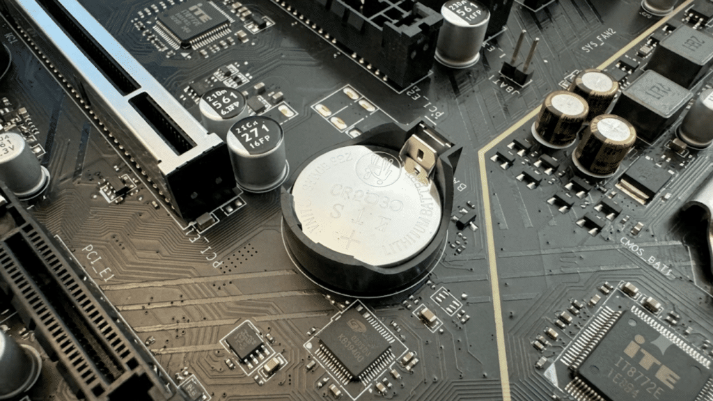 close up of a motherboard showing a cr2032 cmos battery installed beside electronic components and expansion slots