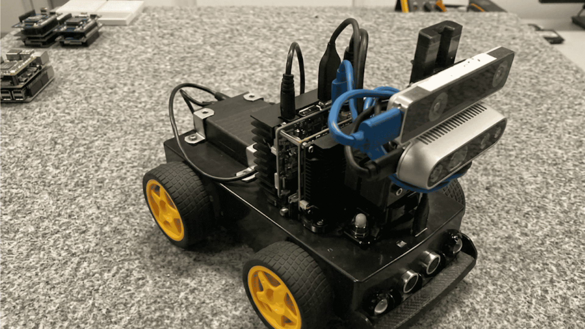 compact black robot with yellow wheels depth cameras sensors and onboard computer mounted on a mobile platform