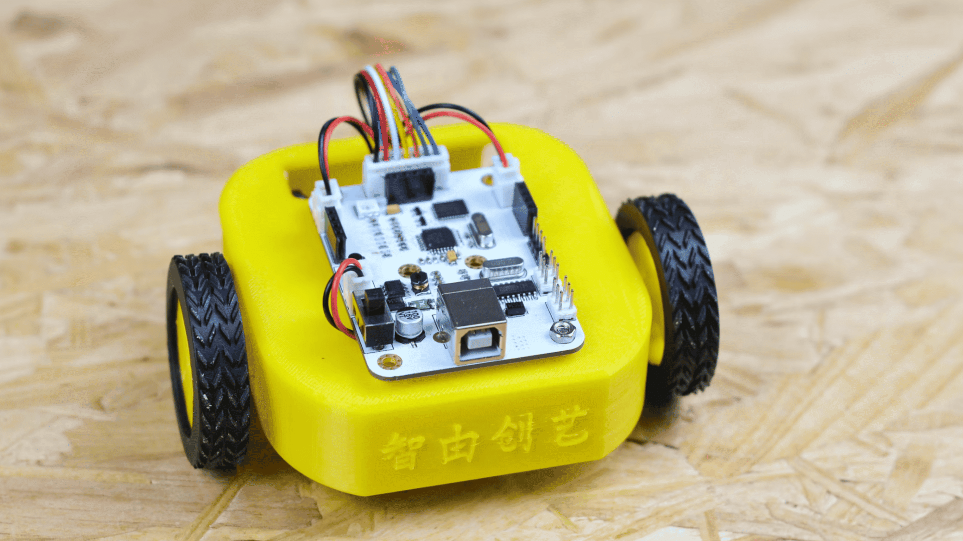 compact yellow two wheel robot with a mounted microcontroller board and colorful jumper wires on top