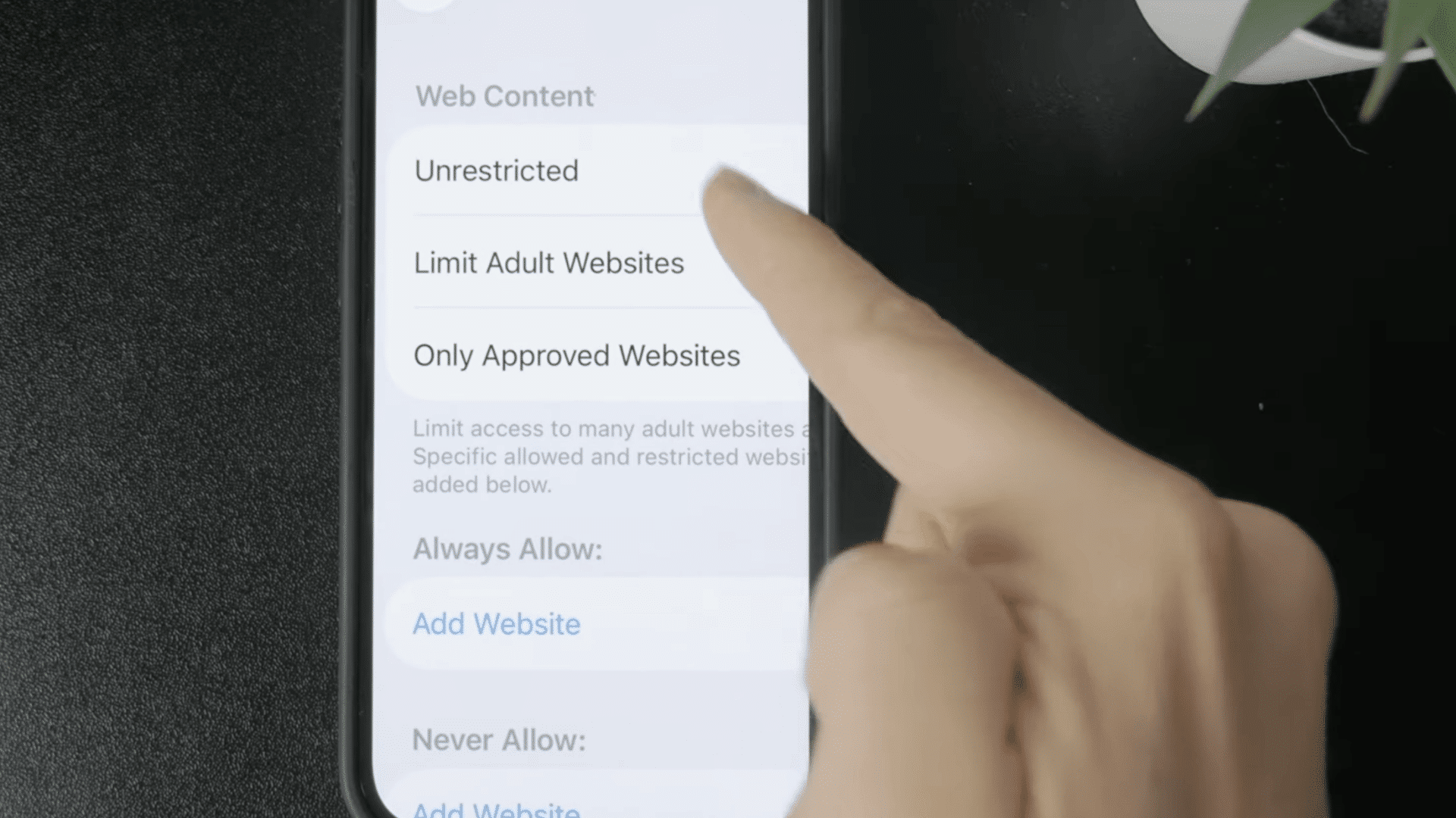 finger choosing unrestricted web content option in iphone settings to adjust website access permissions