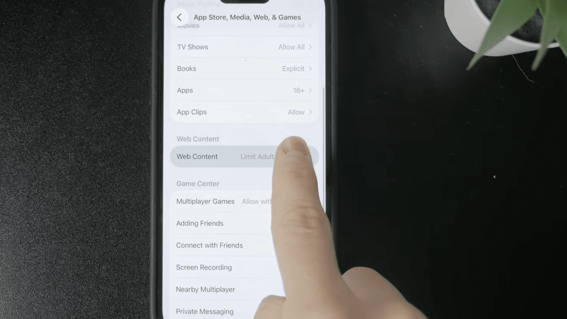 _finger selecting app store media web and games in iphone content and privacy restrictions settings