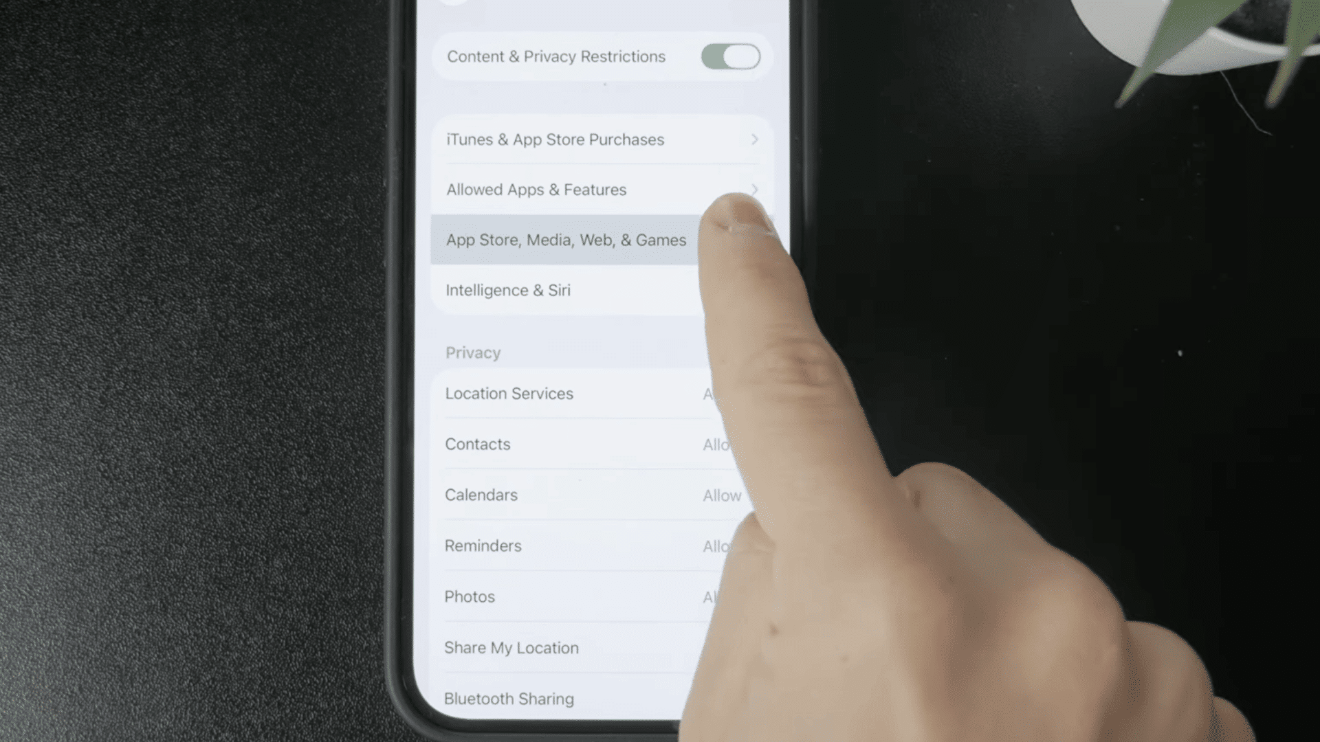 finger selecting web content settings within iphone parental controls to manage website access options