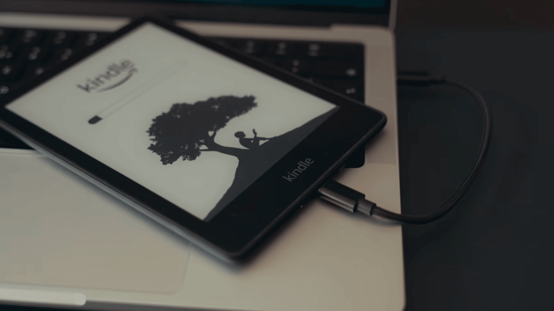 hand connecting a charging cable to the bottom port of a kindle ereader during troubleshooting