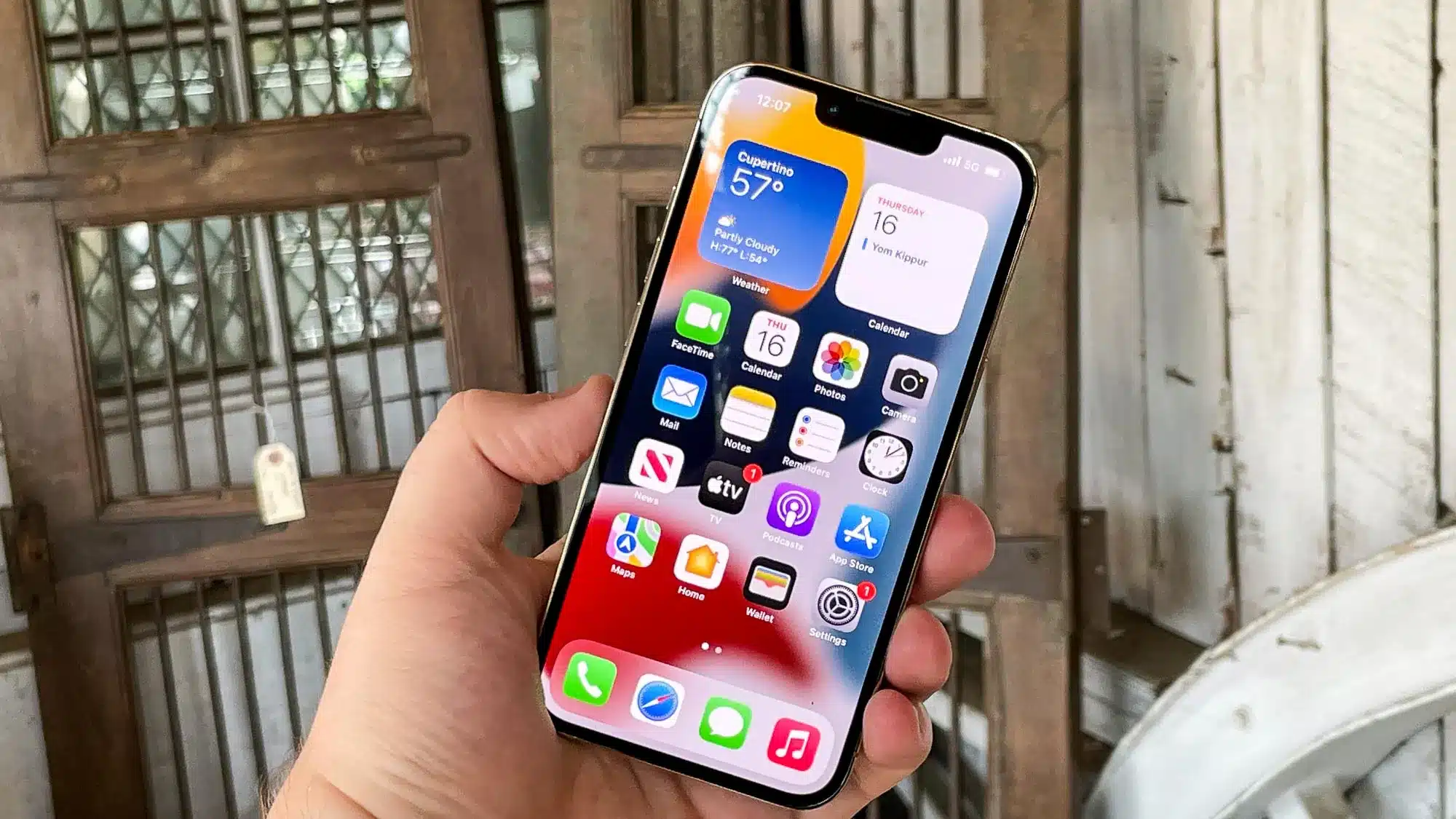 hand holding iphone showing home screen with apps and widgets in everyday setting