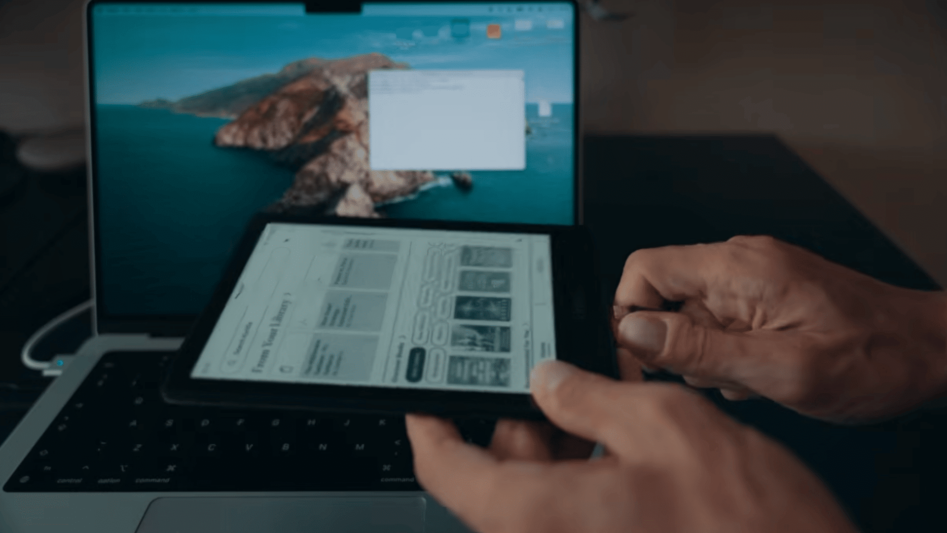 hands holding a kindle ereader connected beside a laptop during a device setup and restore process (1)