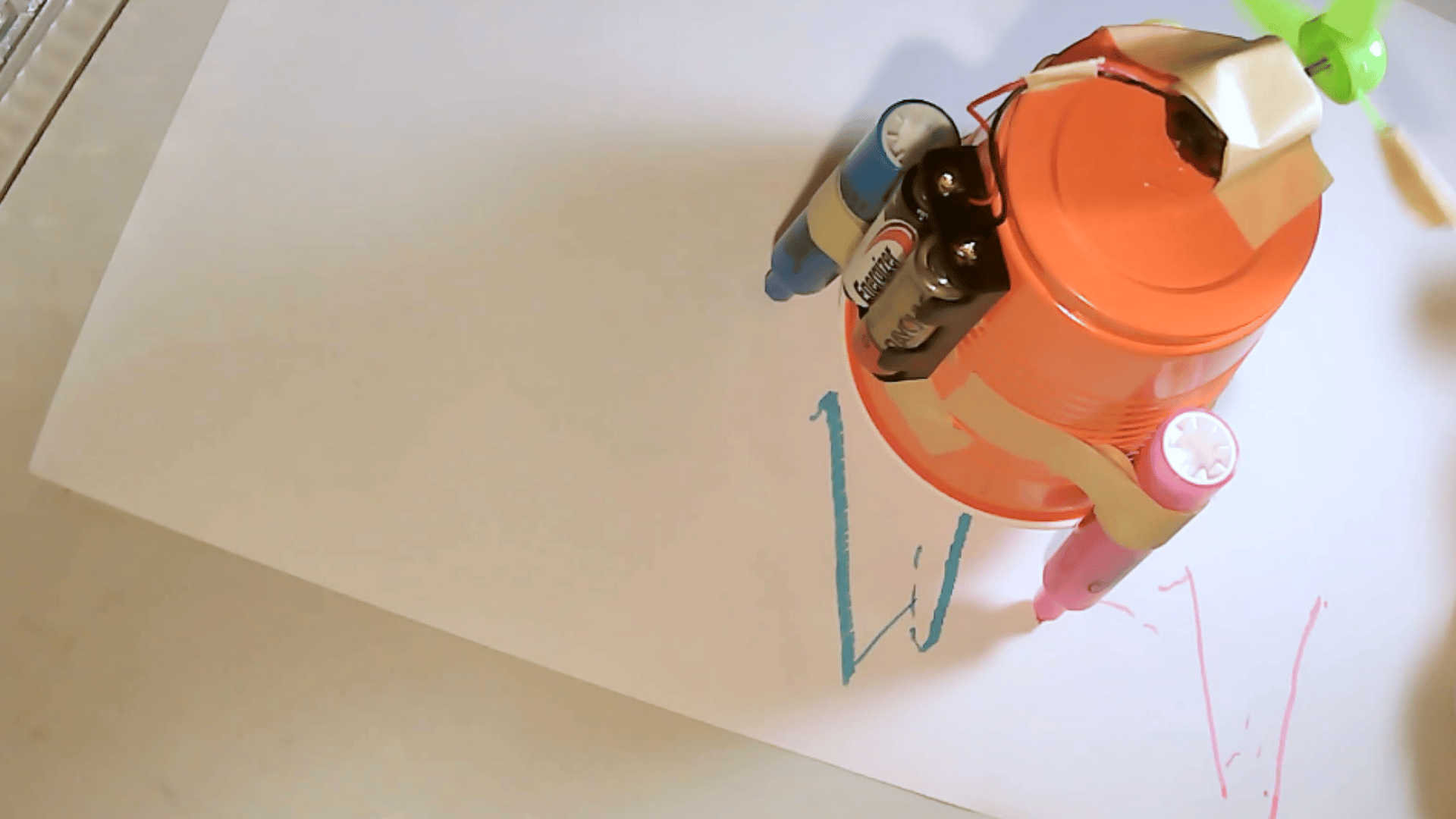 homemade drawing robot built from a plastic cup markers batteries and small motor creating lines on paper