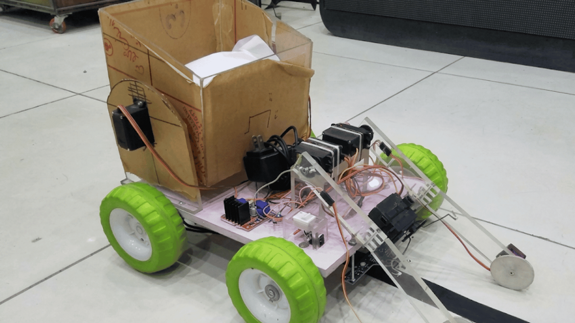 homemade robot cart with green wheels cardboard storage box servo motors and electronic components on a chassis