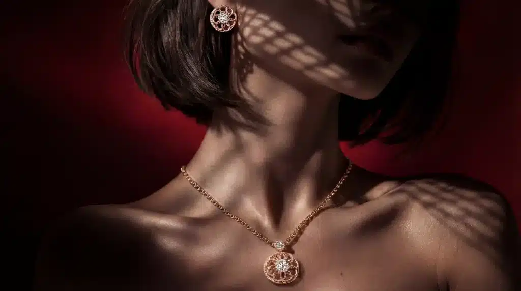 Rose gold necklace and earrings on a woman's neck and ear against dark red background