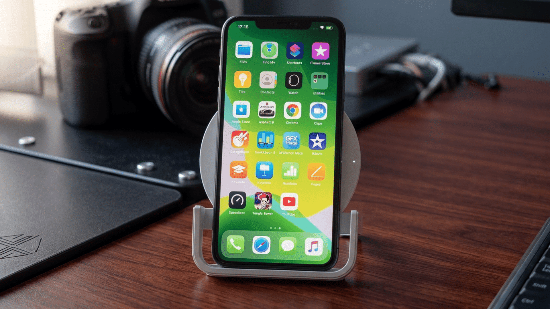 iPhone 11 placed on a Qi wireless charging stand on a desk with camera equipment in the background