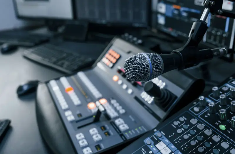 Microphone and audio mixing equipment in a professional recording studio with computers in the background