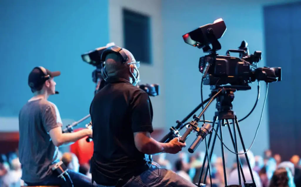 Camera operators filming an event in a brightly lit studio setting