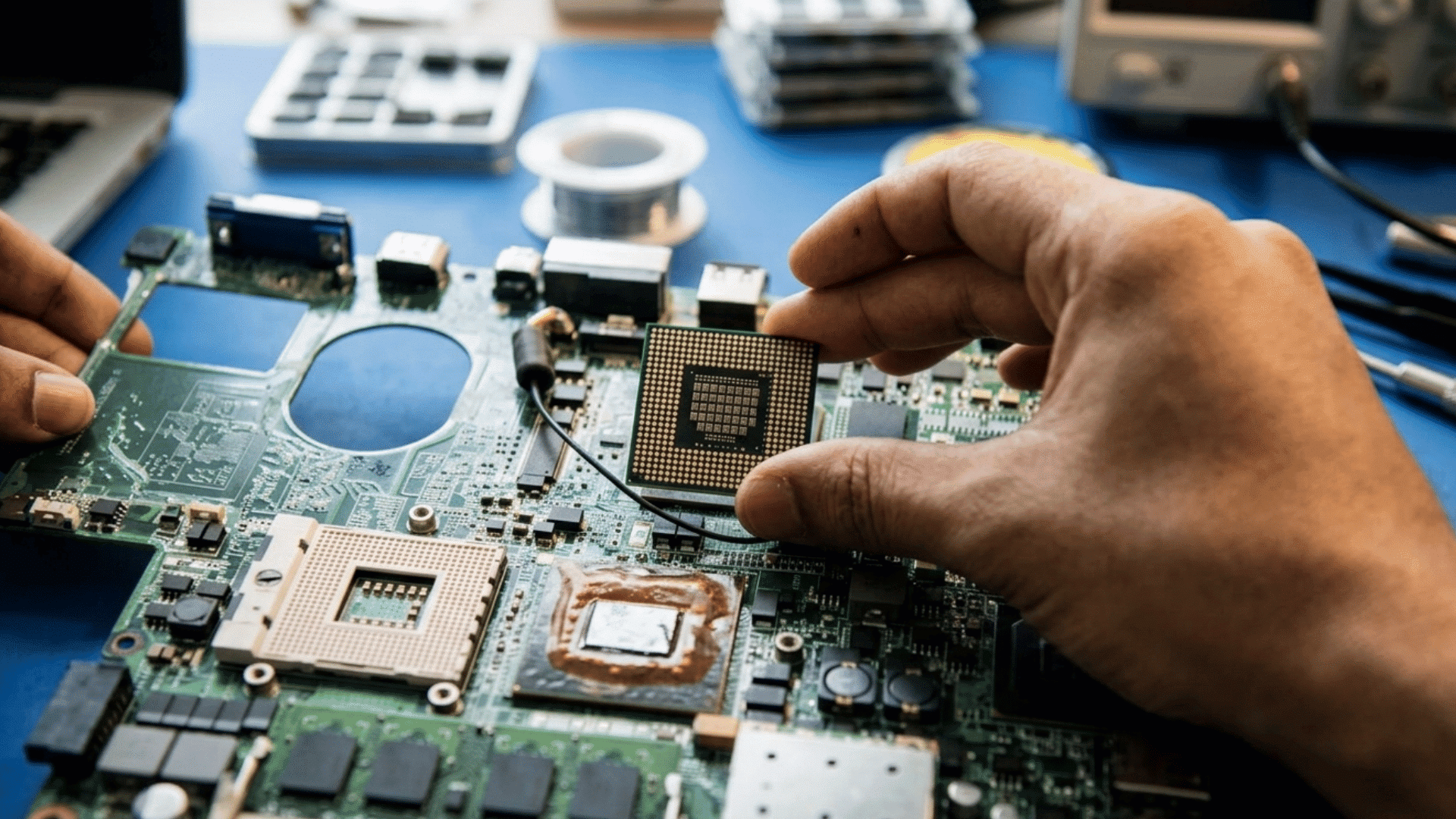 person holding a computer processor above a motherboard socket while preparing to install the cpu into the system board