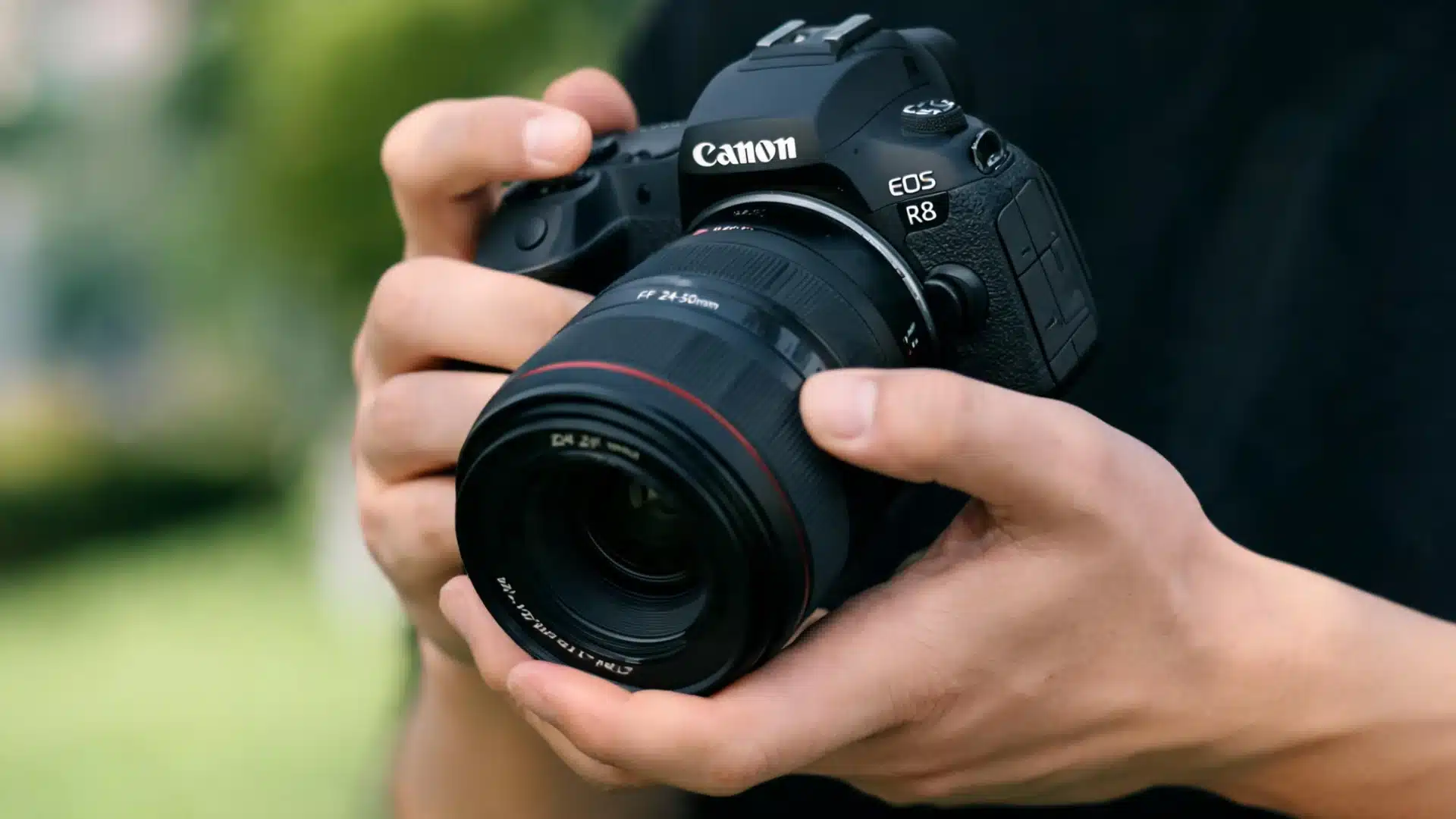Person holding Canon EOS R8 camera with hands on grip and lens