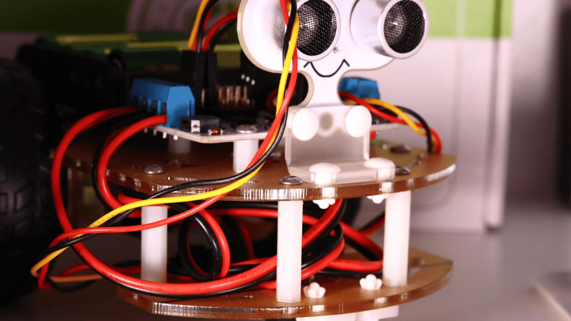 small robot with ultrasonic sensor eyes exposed wiring and electronic modules mounted on a circular frame