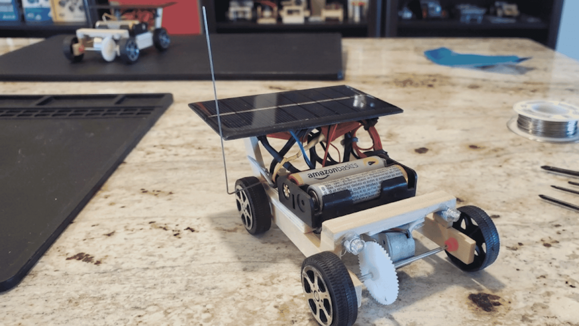 small solar powered toy car with battery pack electric motor and gears resting on a stone countertop