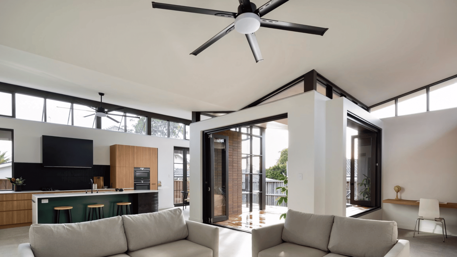 spacious open plan living room with ceiling fans large windows modern kitchen and comfortable seating area