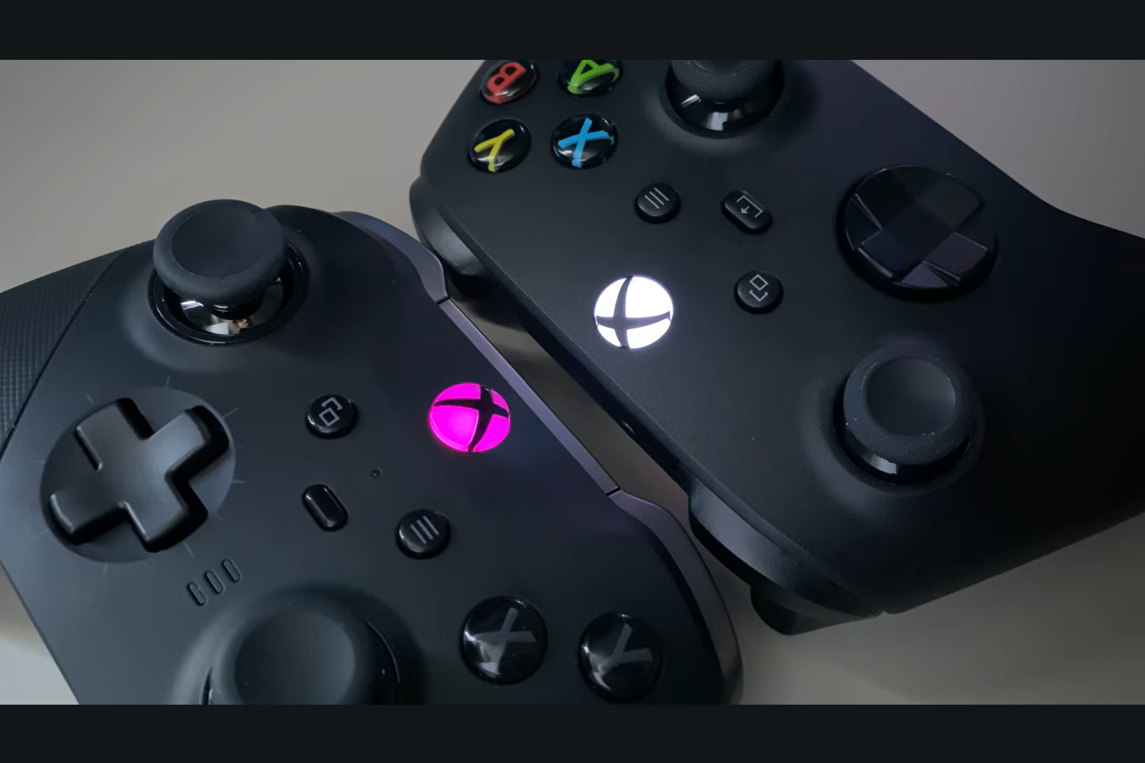 two black xbox controllers placed side by side with illuminated xbox buttons highlighting different controller designs
