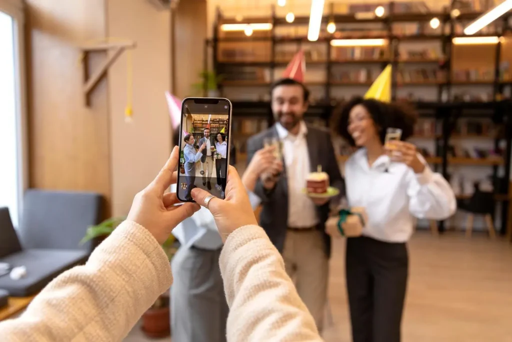 Group of people with party hats posing for a photo in a warmly lit office space