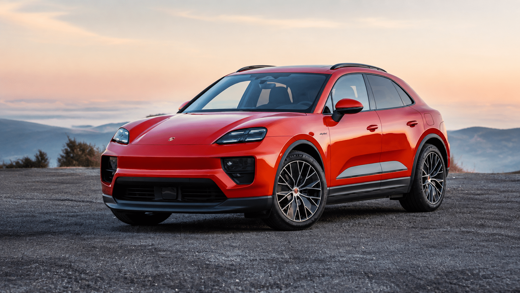 red porsche macan electric suv parked with mountain backdrop sporty front led headlights alloy wheels glossy red paint