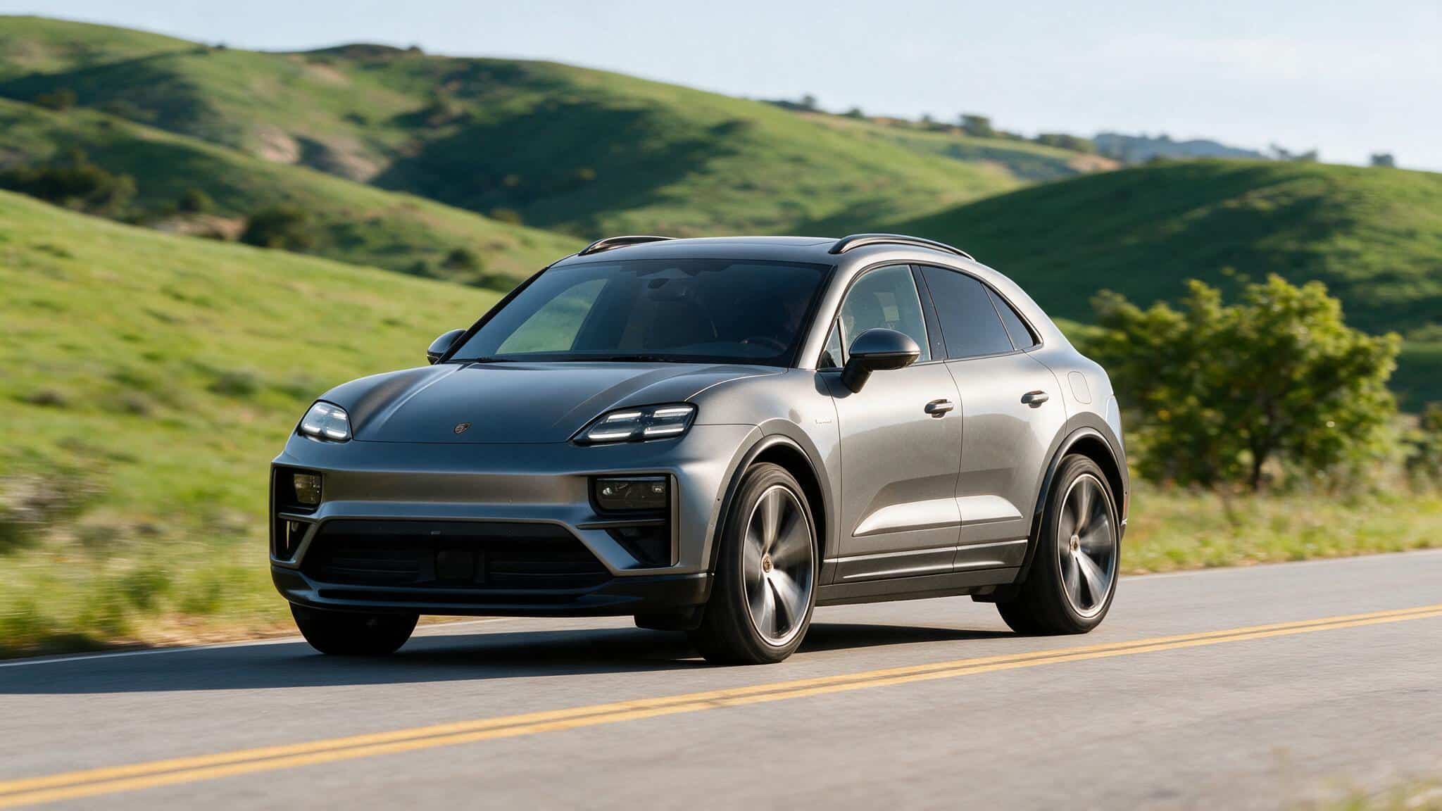 silver porsche macan electric suv on rural road with rolling green hills sleek coupe profile led headlights alloy wheels