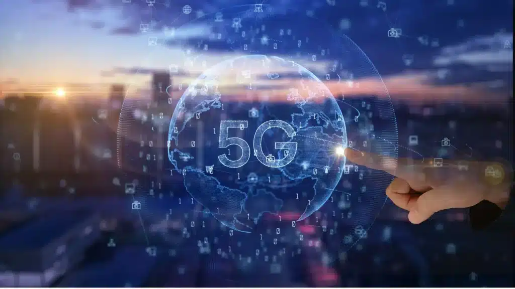 Hand touching digital 5G hologram with city skyline at sunset in background