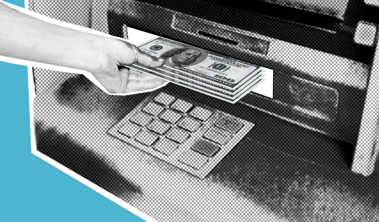 Hand holding stack of cash near ATM deposit slot in grayscale setting