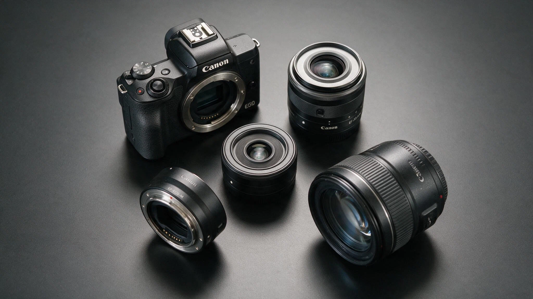 canon eos m50 beside ef m lenses and an ef eos m adapter with a canon ef lens ready to mount