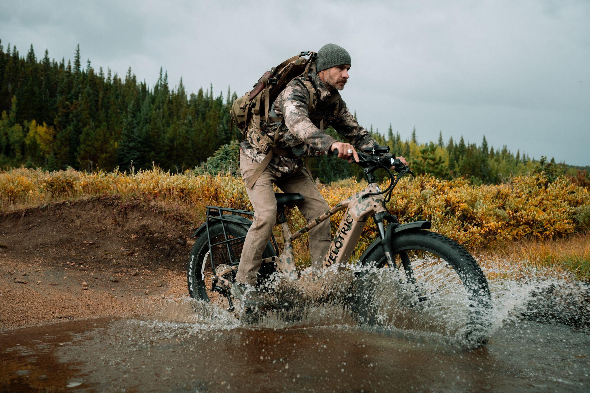 Man riding an electric bike through muddy terrain in a lush forest setting