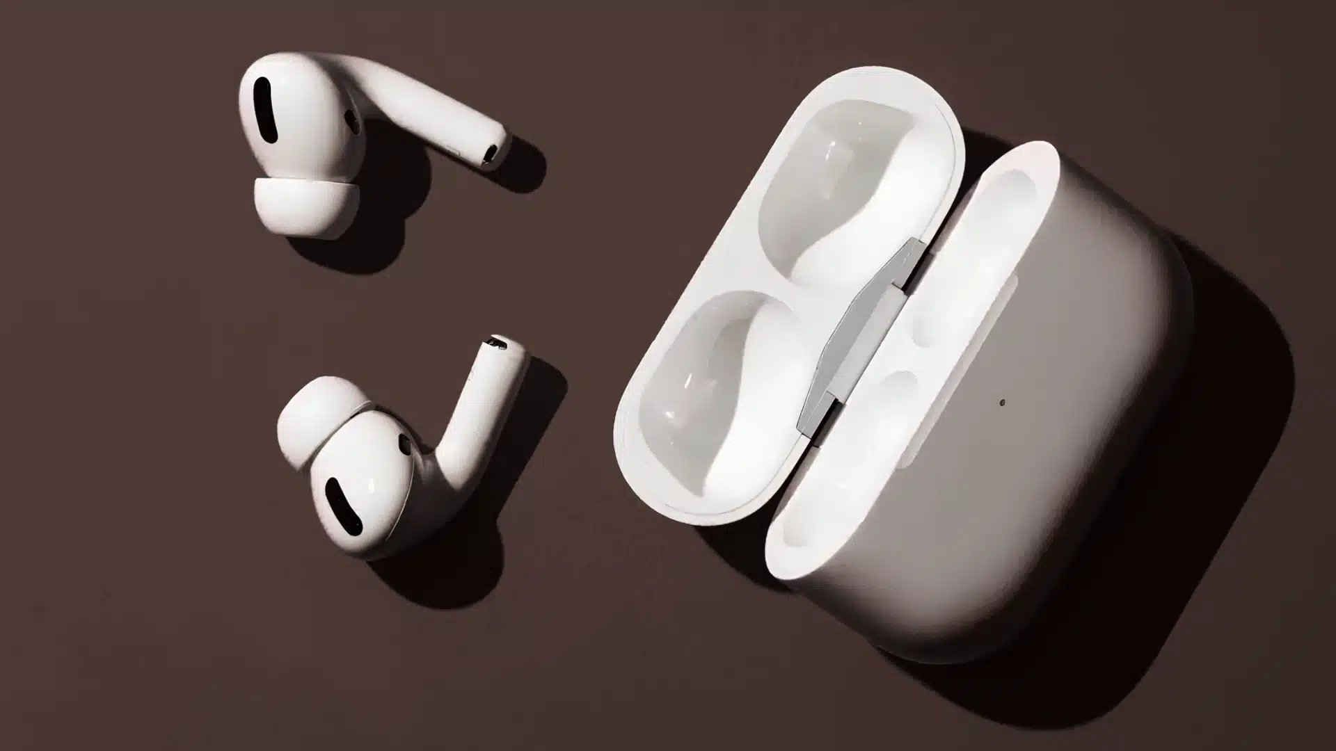 white airpods pro earbuds and open charging case on a dark surface with strong shadows