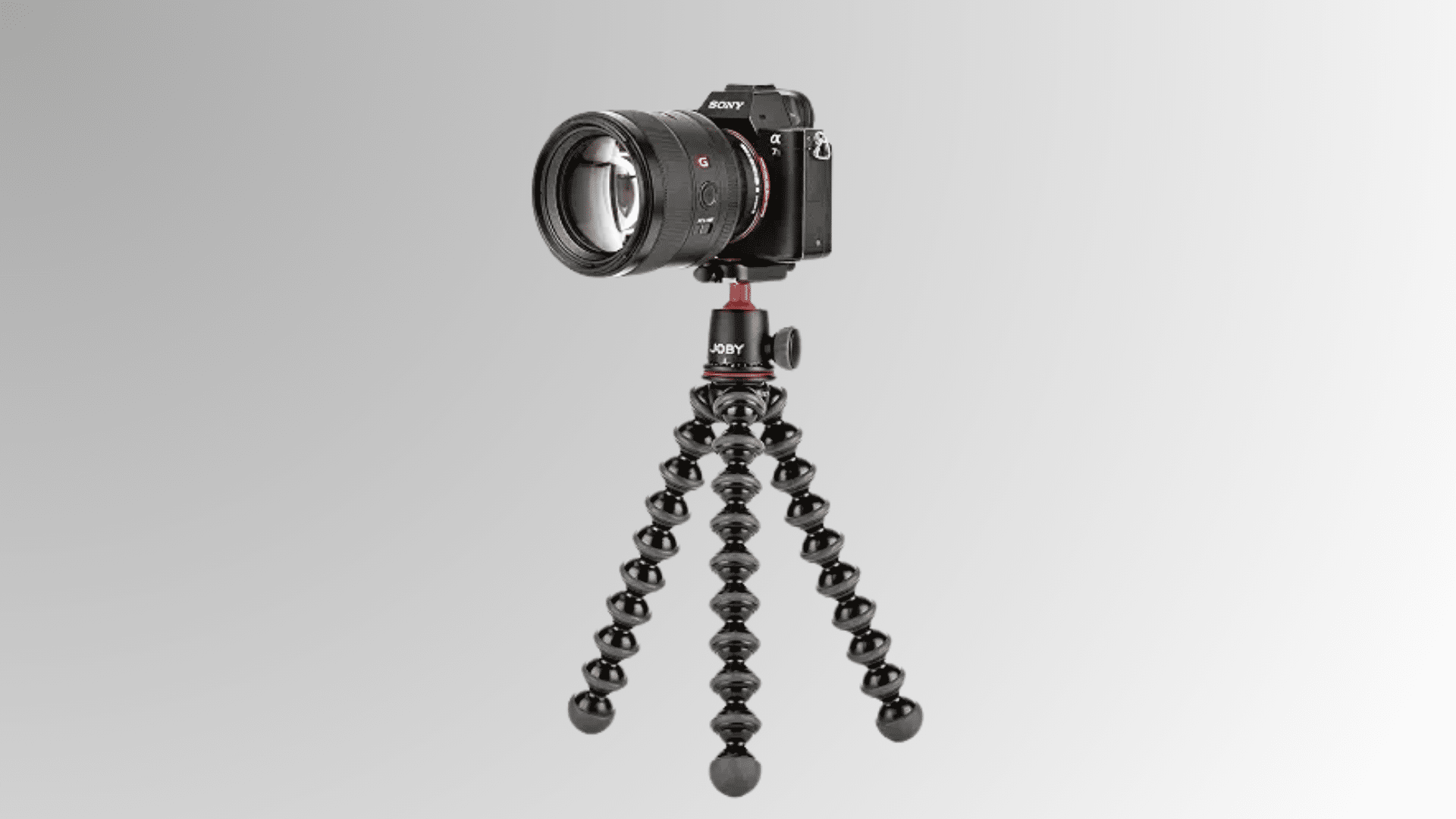 camera with lens attached to a flexible tabletop tripod on white background