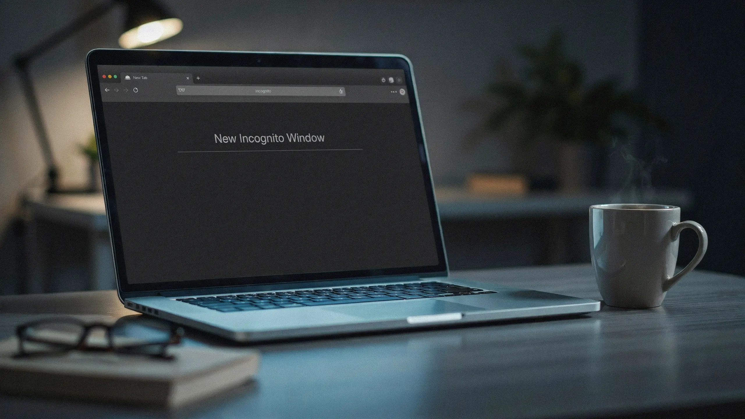 laptop showing incognito browser window on a desk with coffee cup and blurred background in a dim workspace