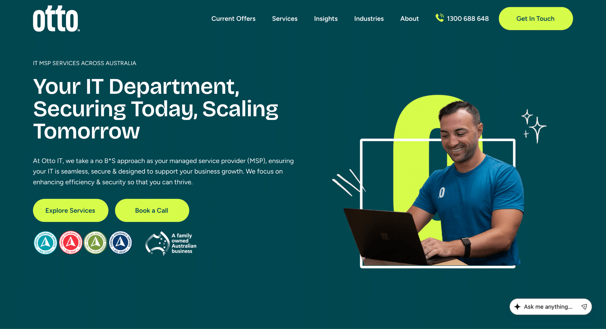 Person in blue shirt smiling while using a laptop with teal background