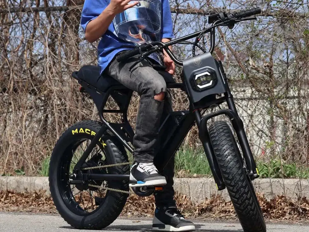 Person sitting on a black electric bike parked on a paved outdoor path